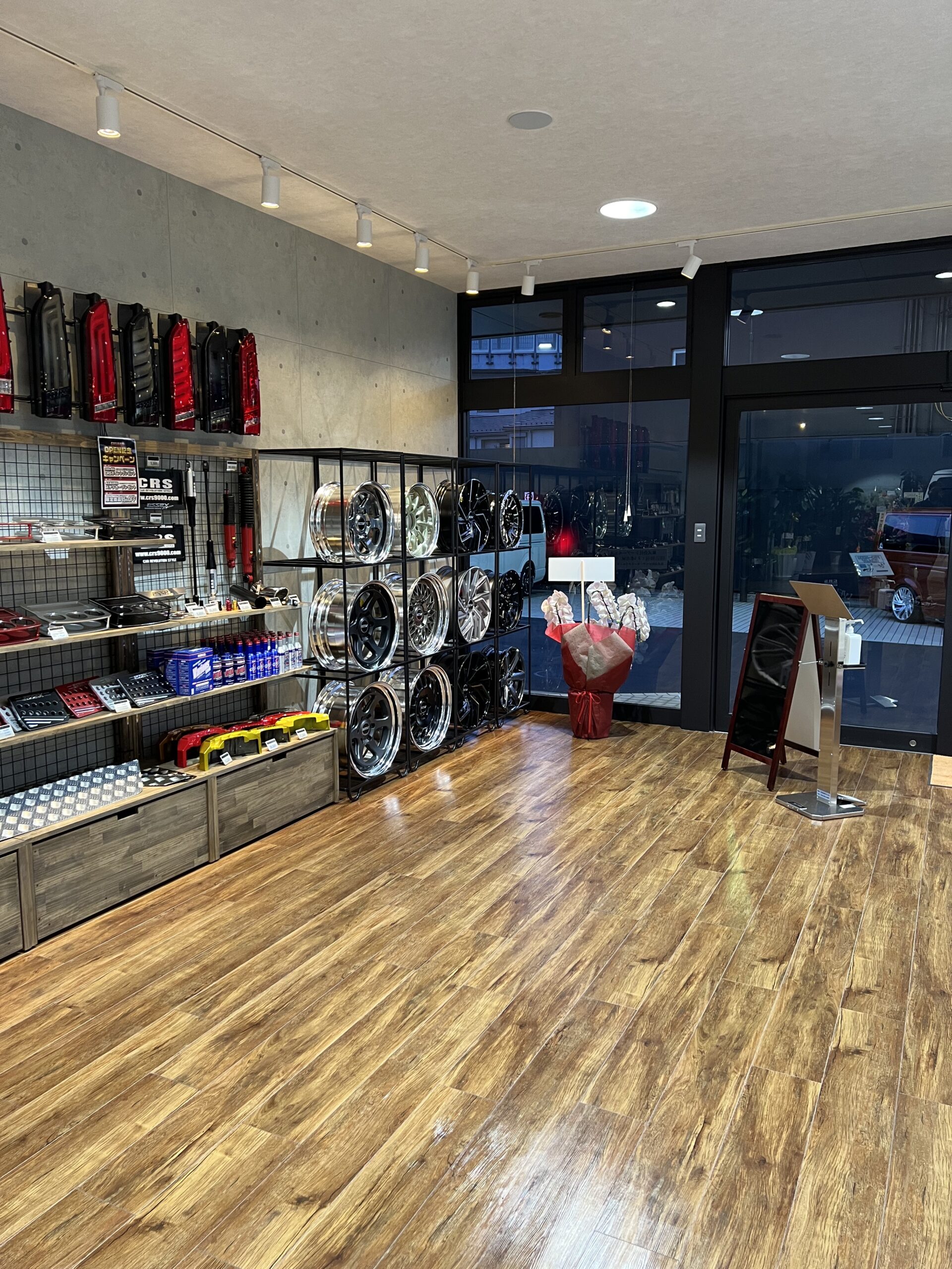 木の床と什器棚、ライティングレール、ガラス面がある物販店の内装